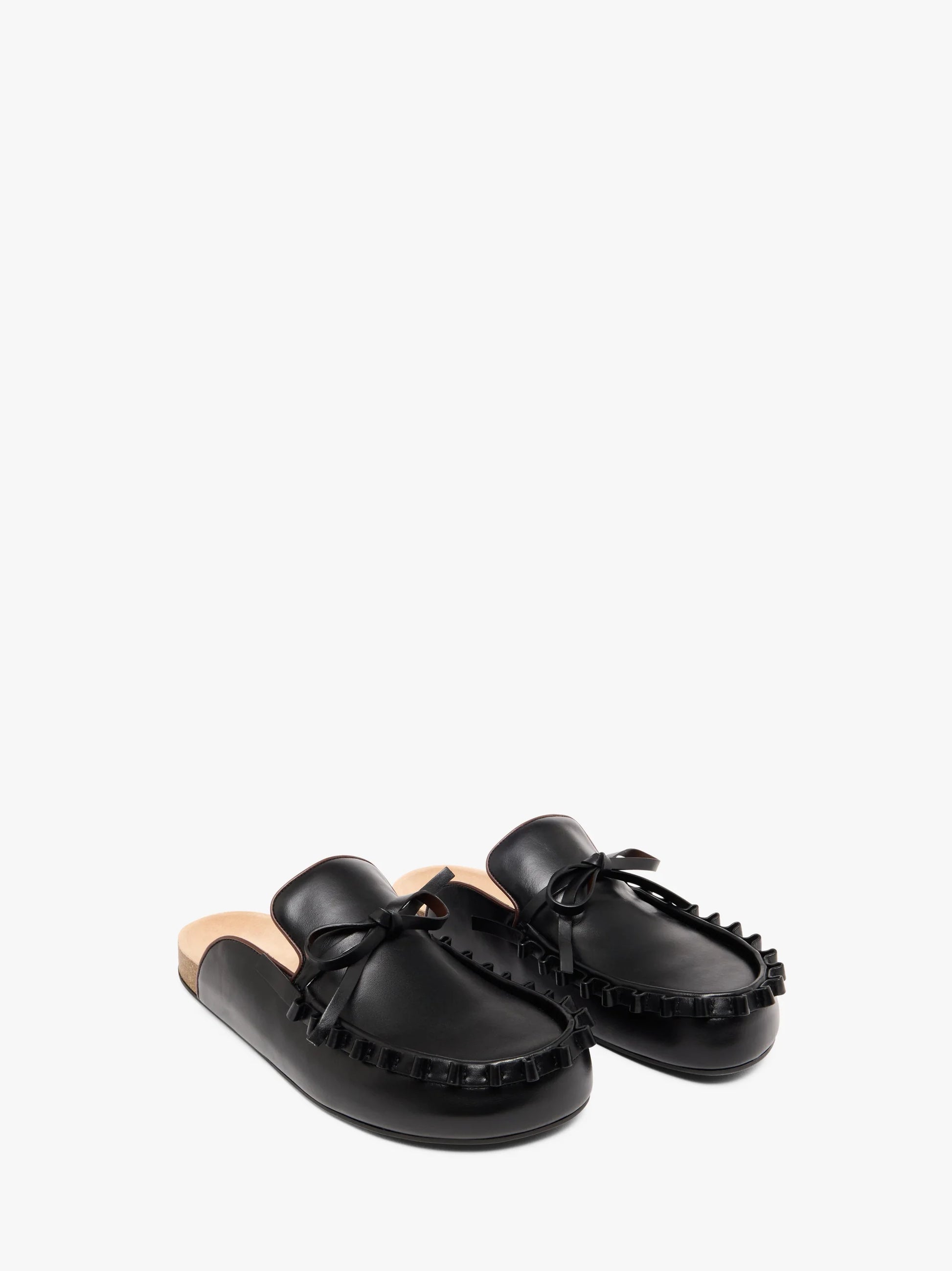 Pair of black leather mules with beige soles on a white background