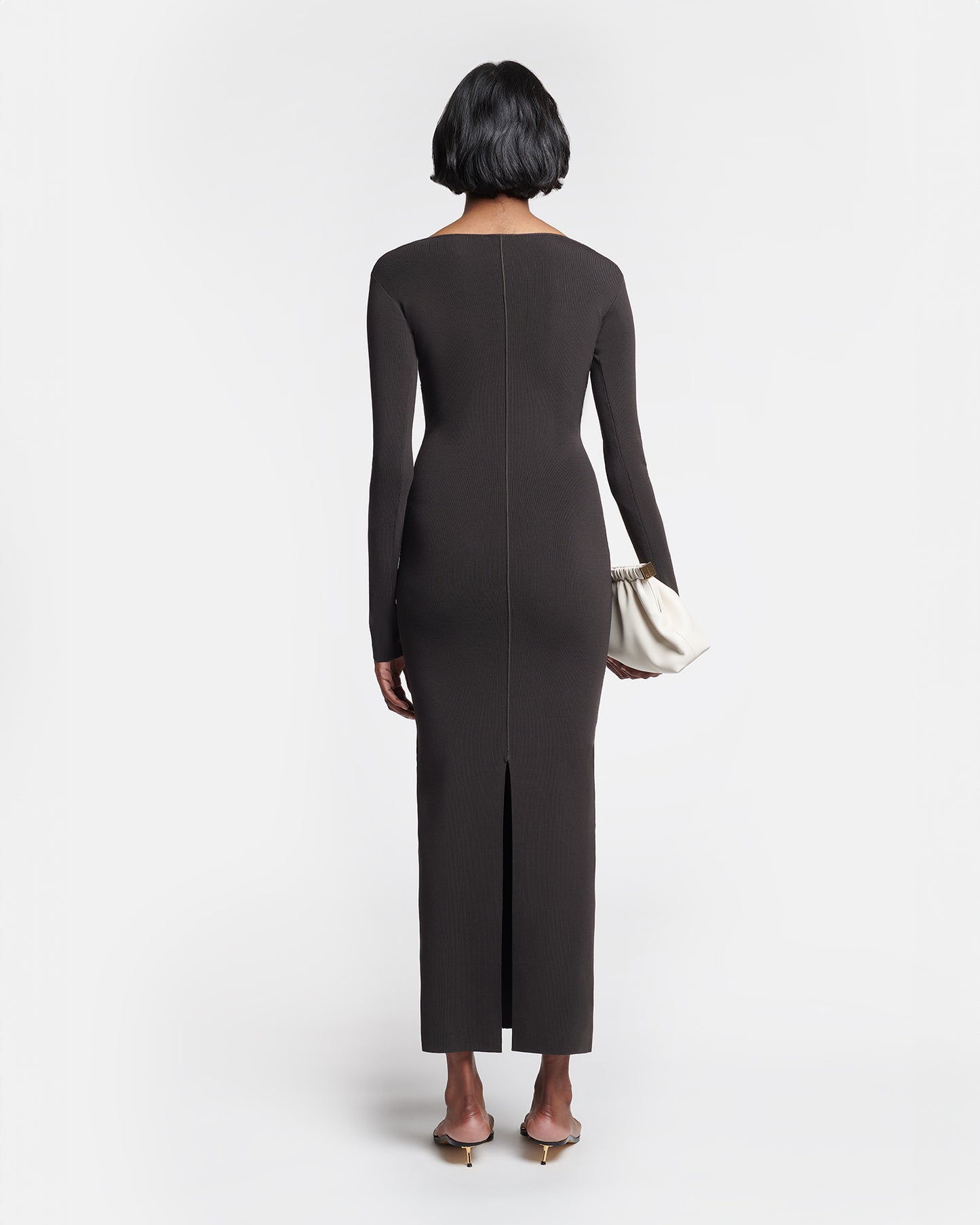 Woman wearing a black dress with a slit on a white background