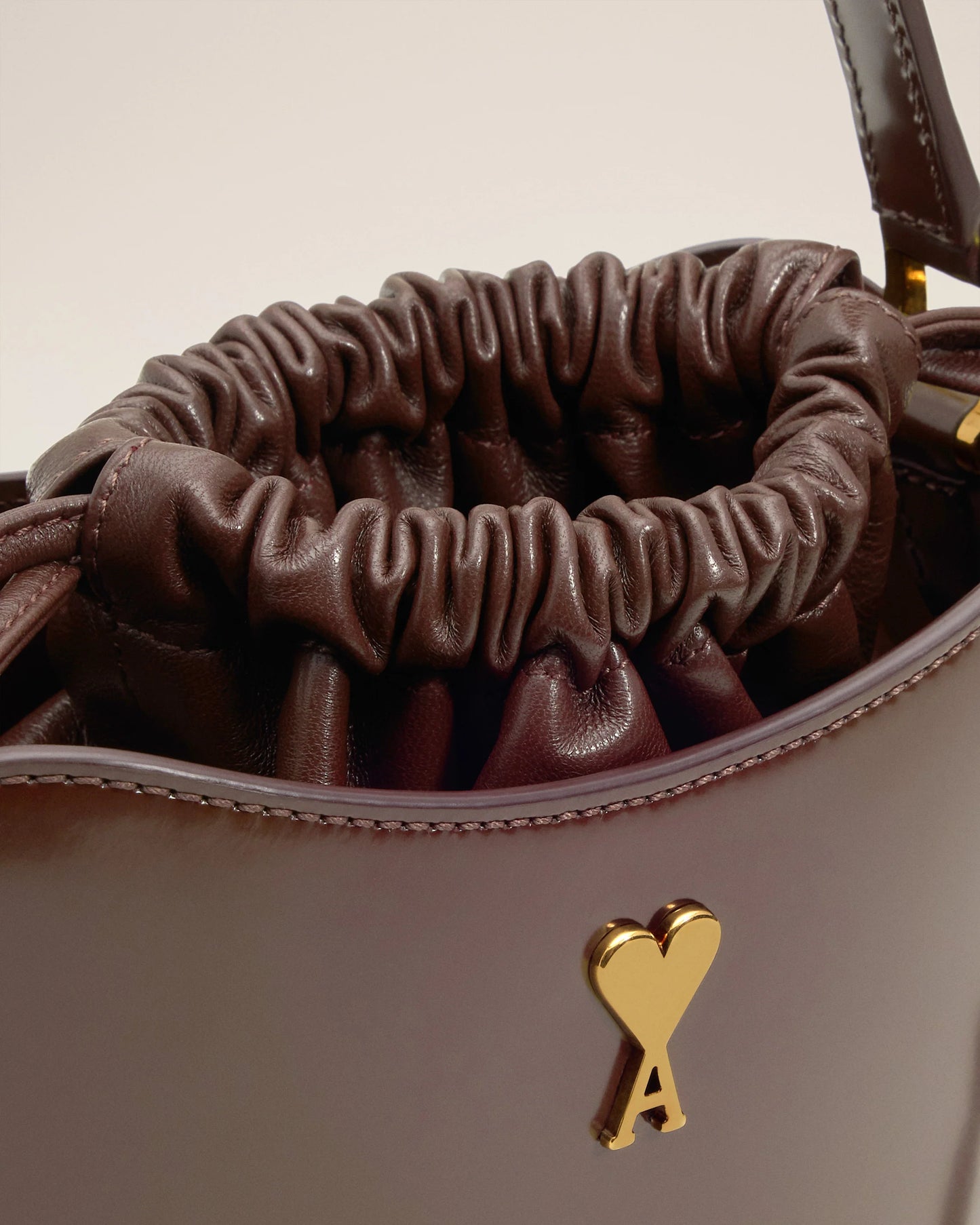 Brown leather drawstring bag with a heart-shaped logo on a white background