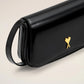 Person holding a black handbag with a gold emblem against a neutral background ami paris