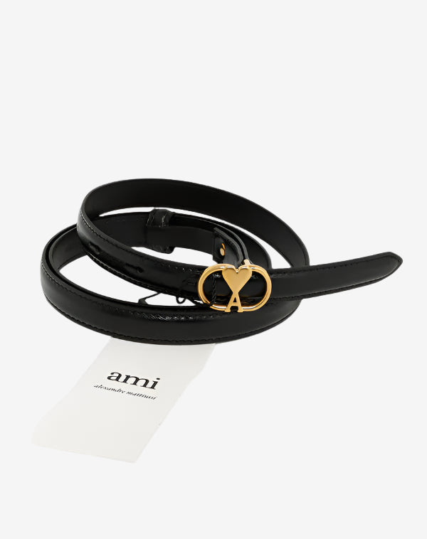 Black belt with gold heart-shaped buckle on a white background, featuring the 'ami' brand.