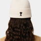 Beige knit beanie with a black heart emblem on a light gray background