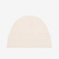 Beige knit beanie with a black heart emblem on a light gray background