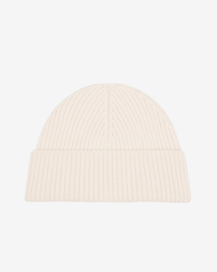 Beige knit beanie with a black heart emblem on a light gray background