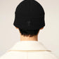 Black beanie hat on a light beige background