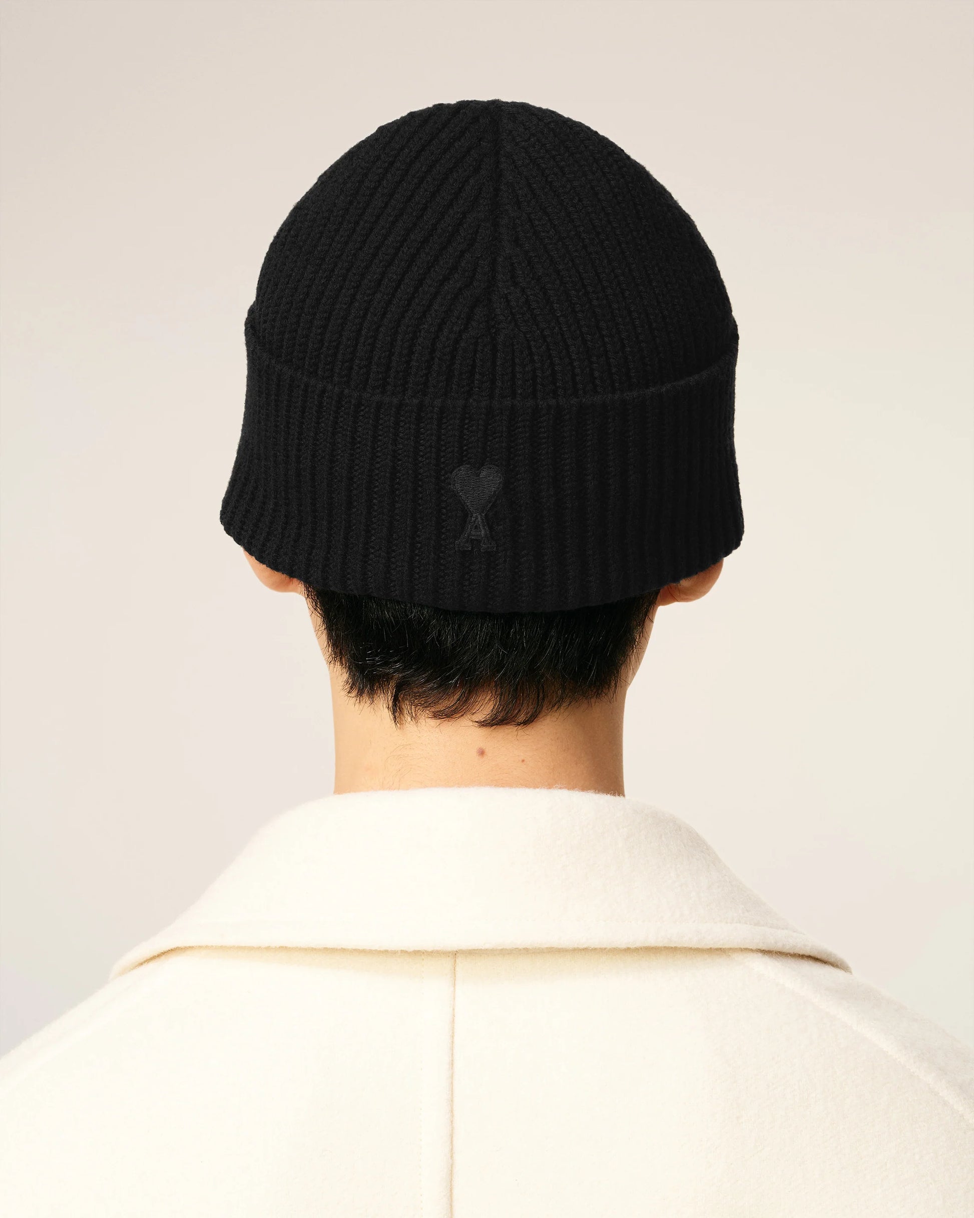 Black beanie hat on a light beige background