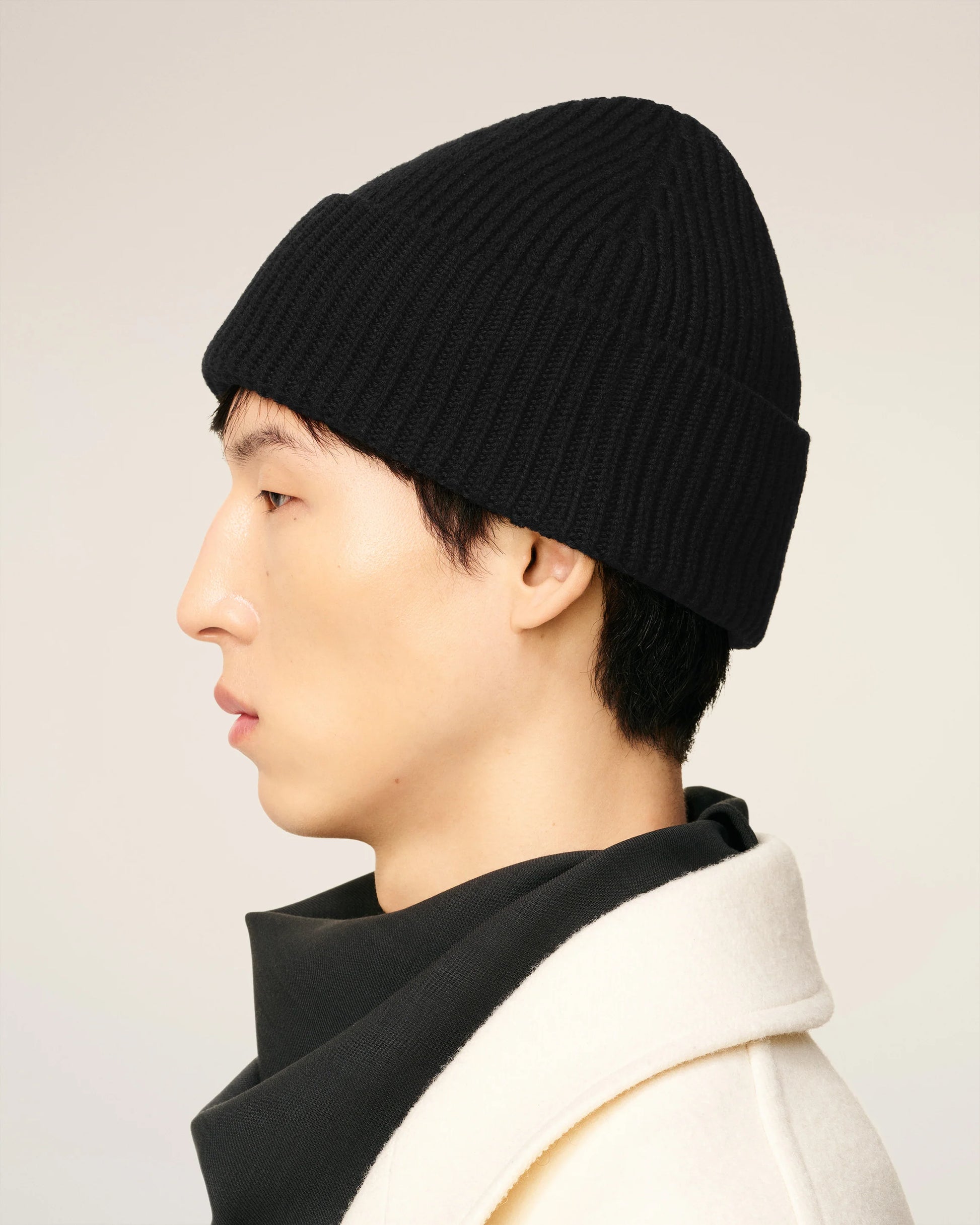 Black beanie hat on a light beige background
