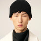 Black beanie hat on a light beige background