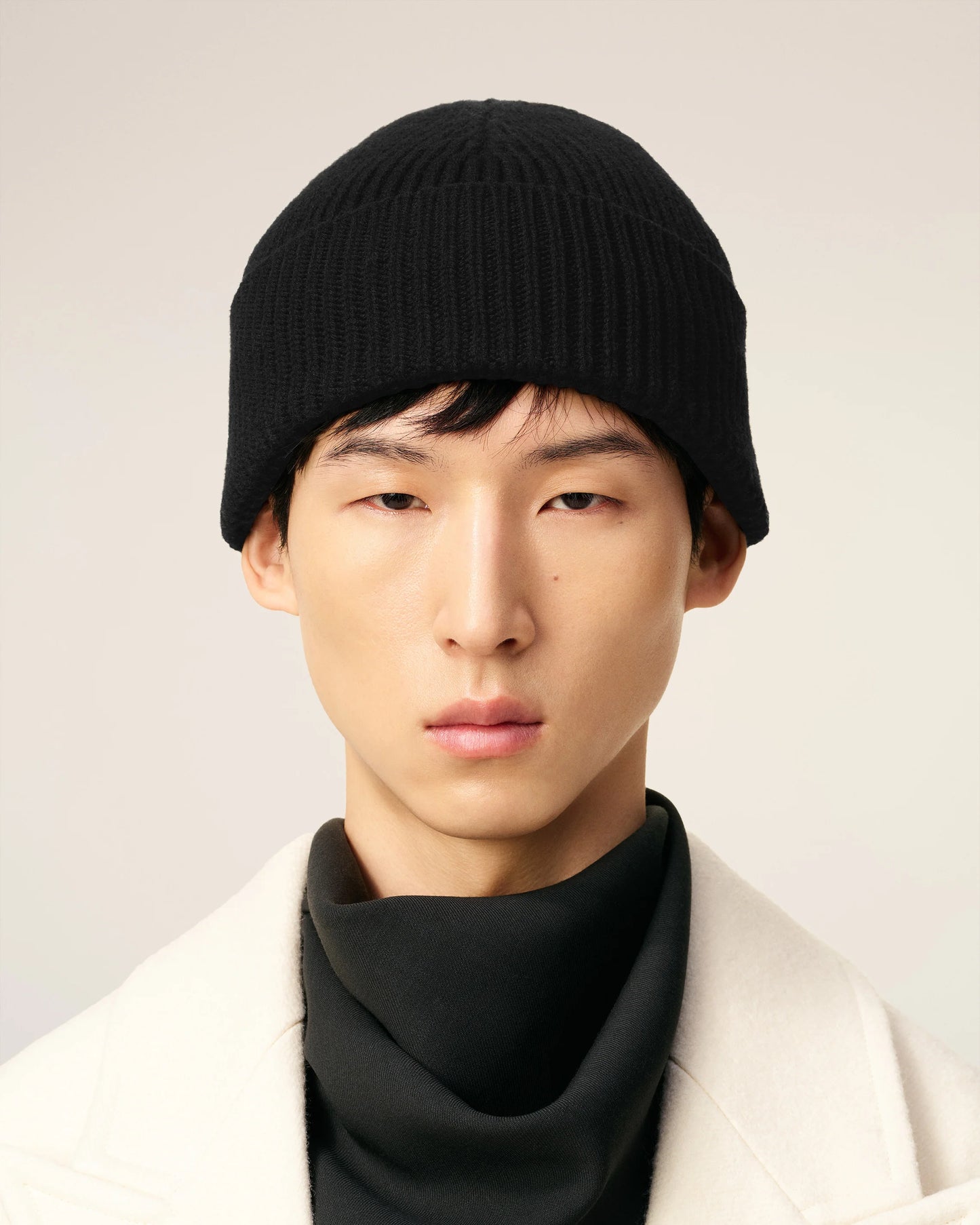 Black beanie hat on a light beige background