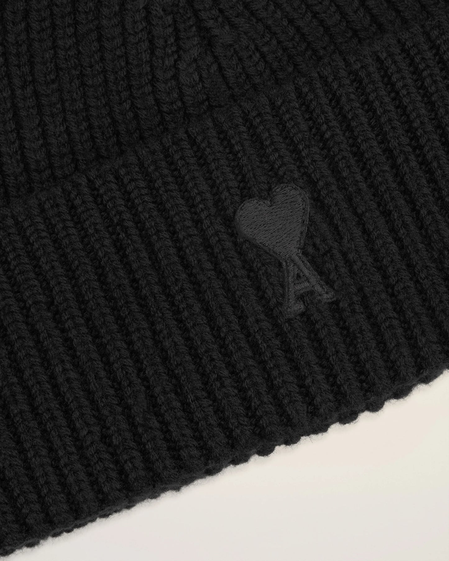 Black beanie hat on a light beige background
