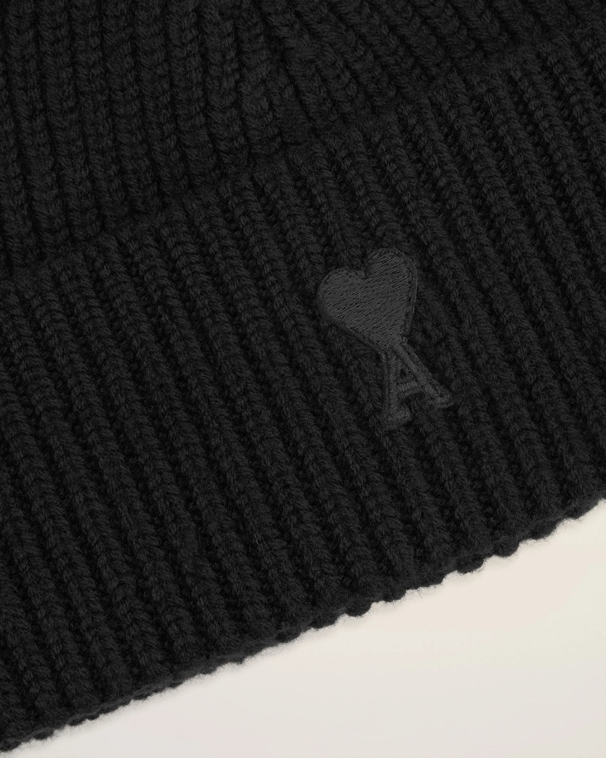 Black beanie hat on a light beige background