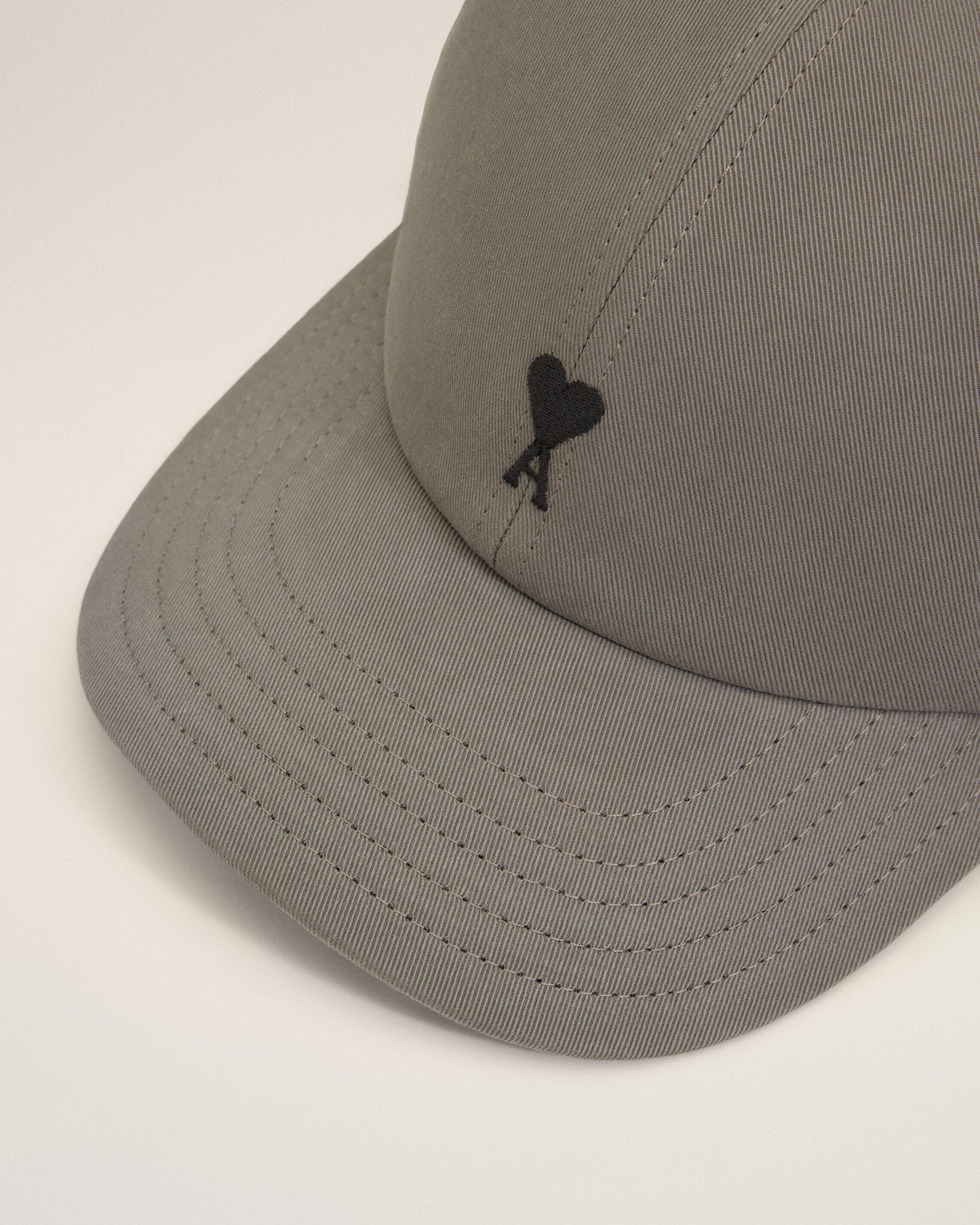 Gray cap with a black logo on a beige background ami paris