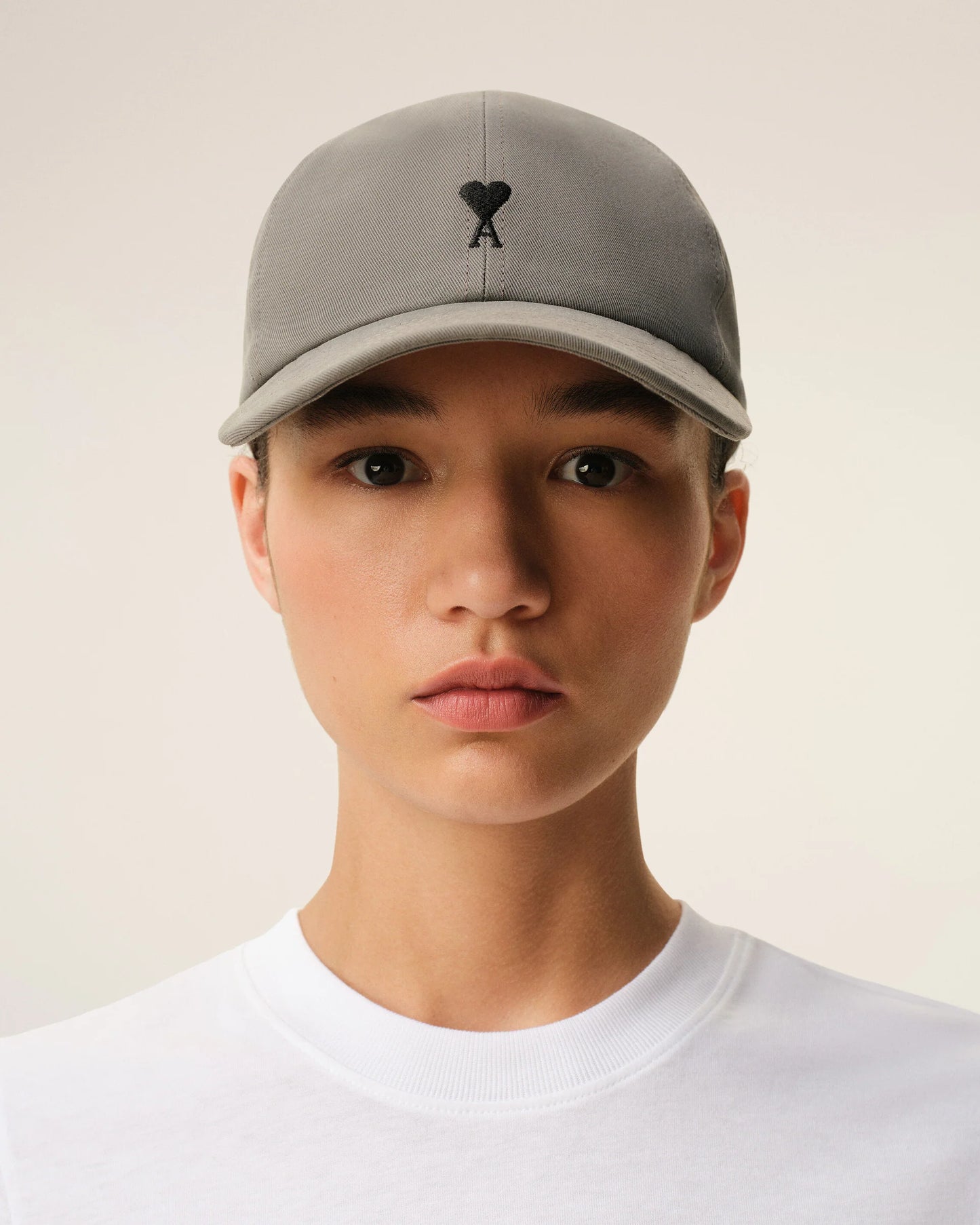 Gray cap with a black logo on a beige background ami paris