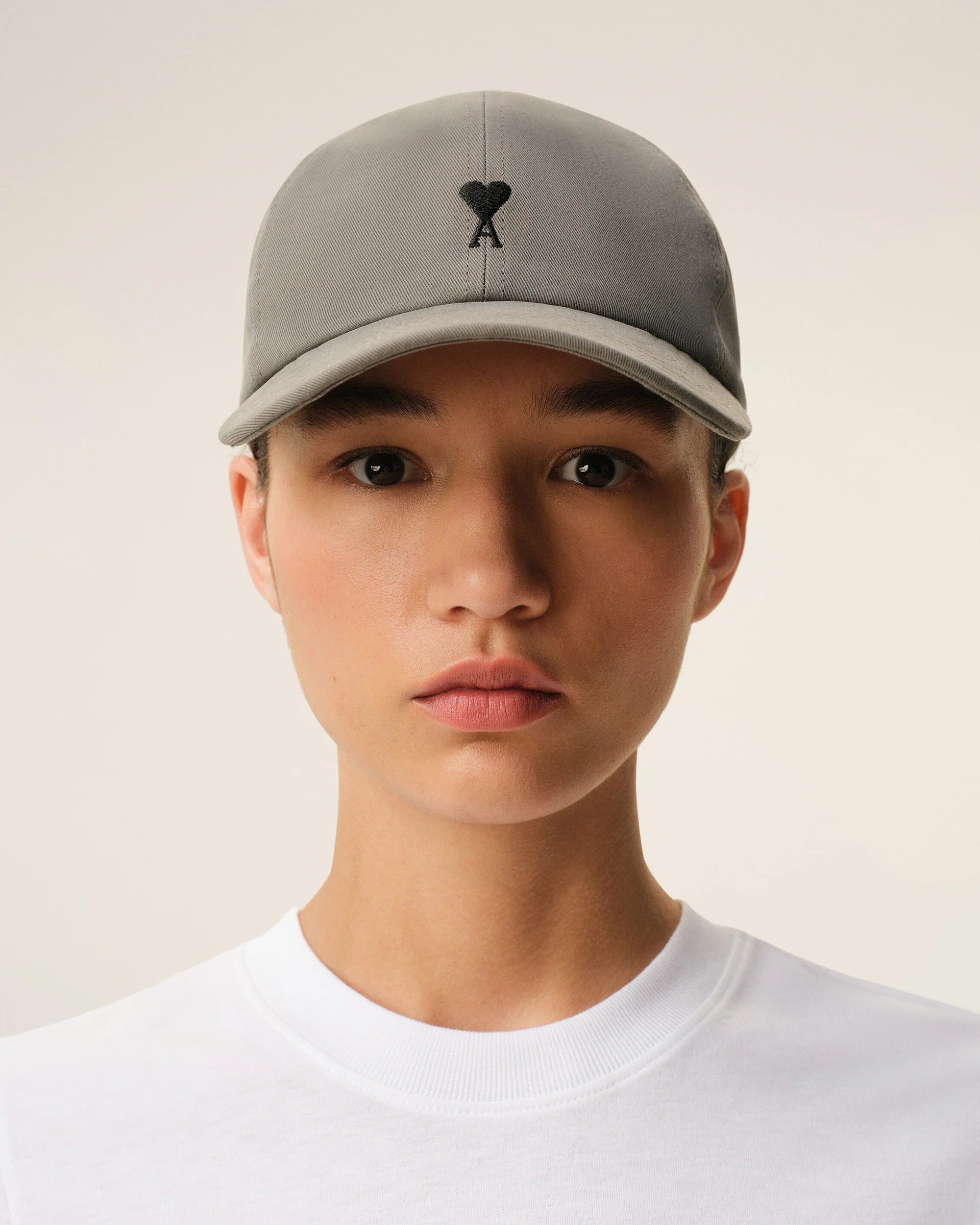 Gray cap with a black logo on a beige background ami paris
