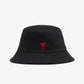 Black bucket hat with a red heart logo on a light beige background