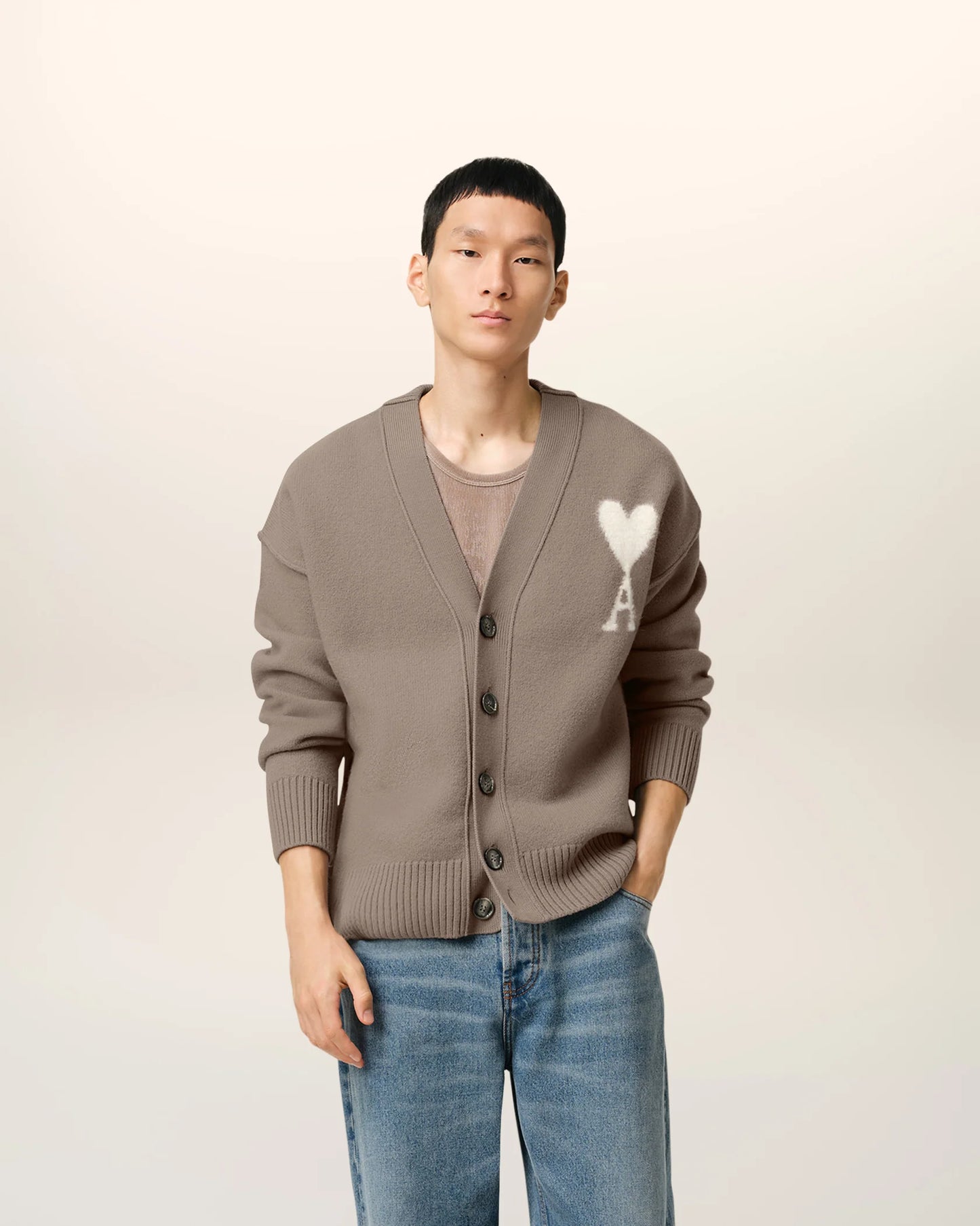 Brown cardigan with a heart and 'AMI' logo on a beige background