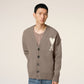 Brown cardigan with a heart and 'AMI' logo on a beige background