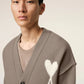 Brown cardigan with a heart and 'AMI' logo on a beige background