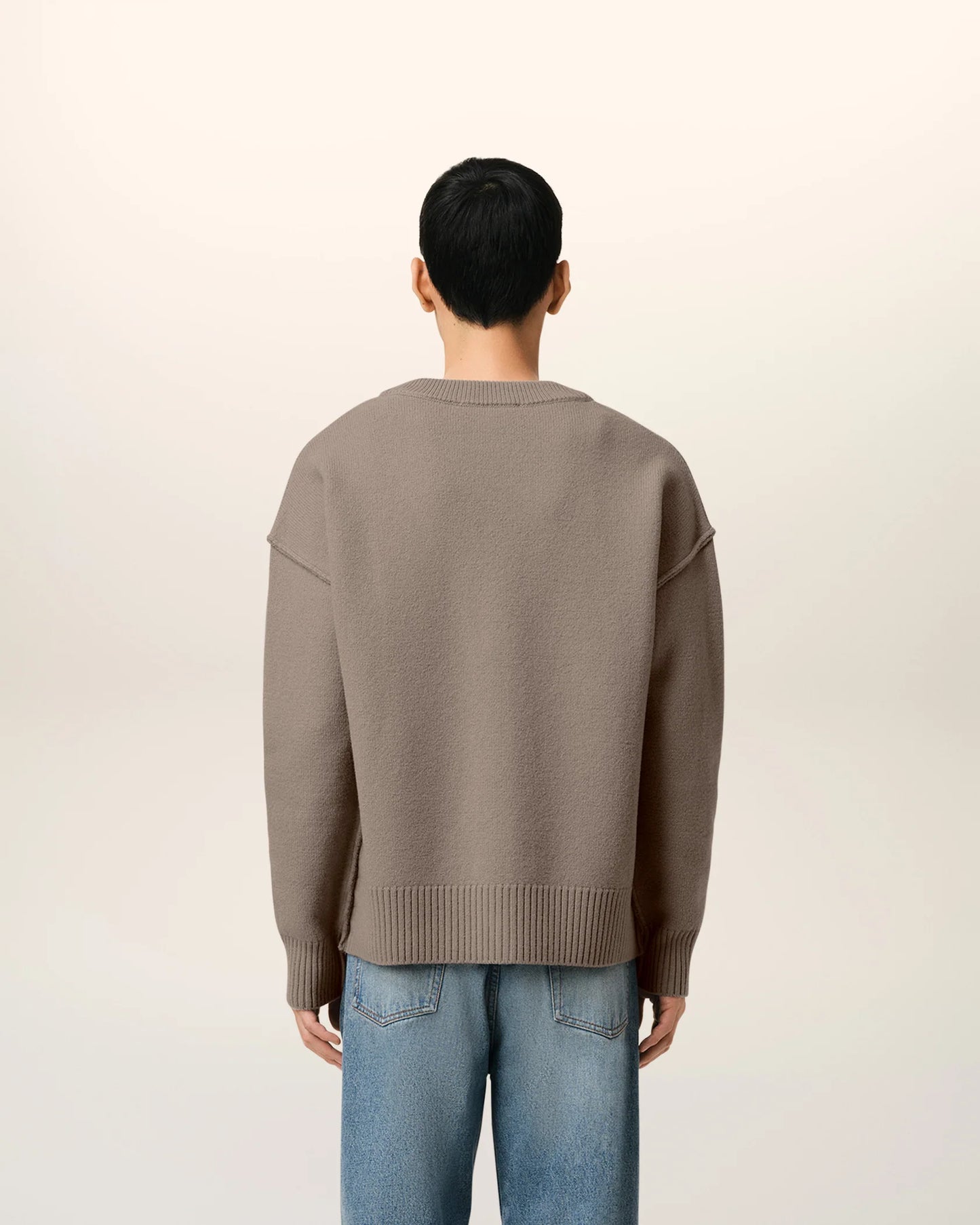 Brown cardigan with a heart and 'AMI' logo on a beige background