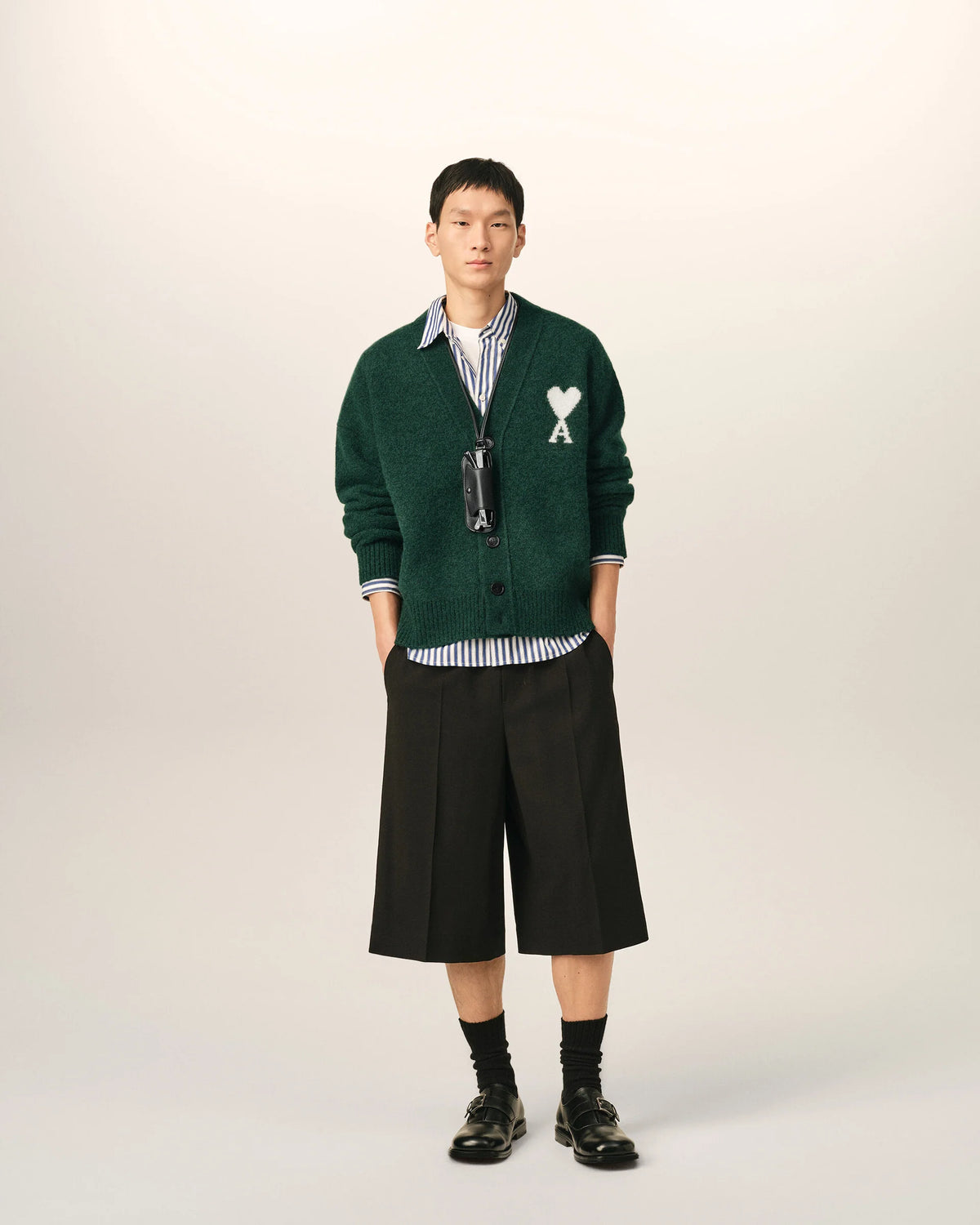 Green cardigan with a heart and 'A' emblem on a beige background