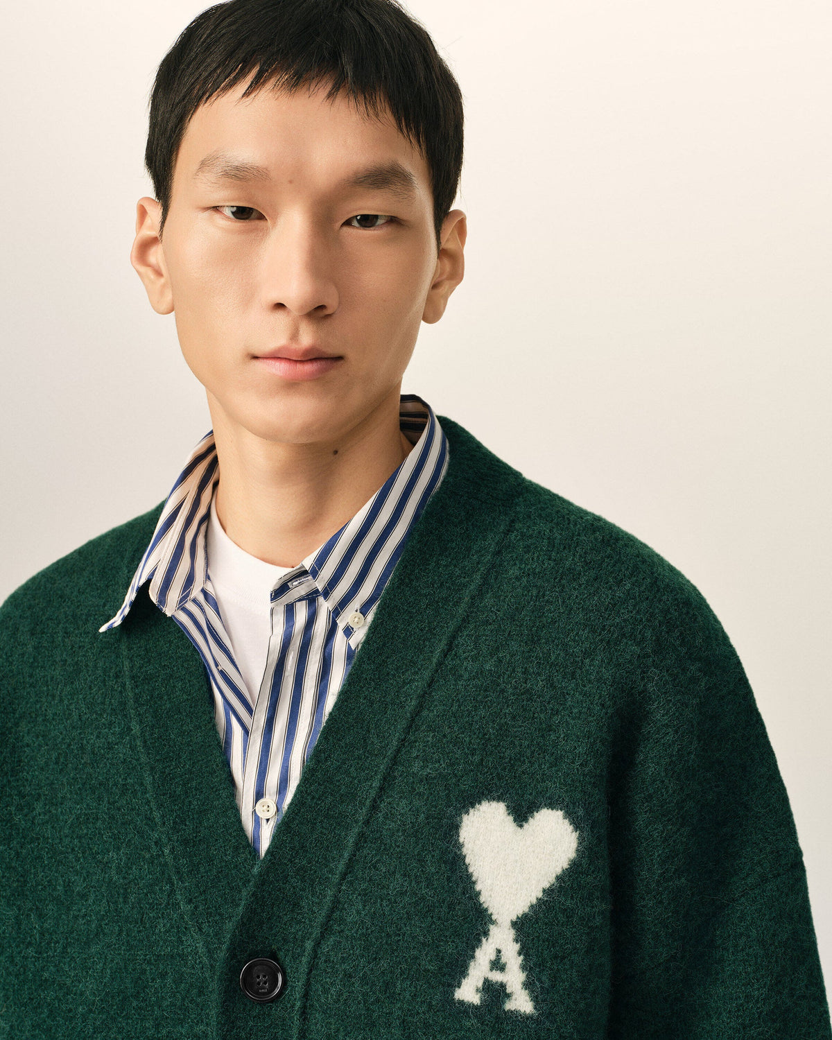Green cardigan with a heart and 'A' emblem on a beige background