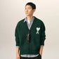 Green cardigan with a heart and 'A' emblem on a beige background
