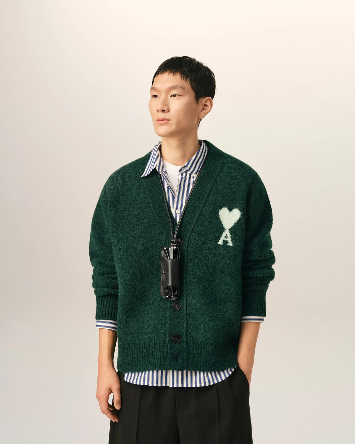 Green cardigan with a heart and 'A' emblem on a beige background