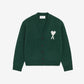 Green cardigan with a heart and 'A' emblem on a beige background