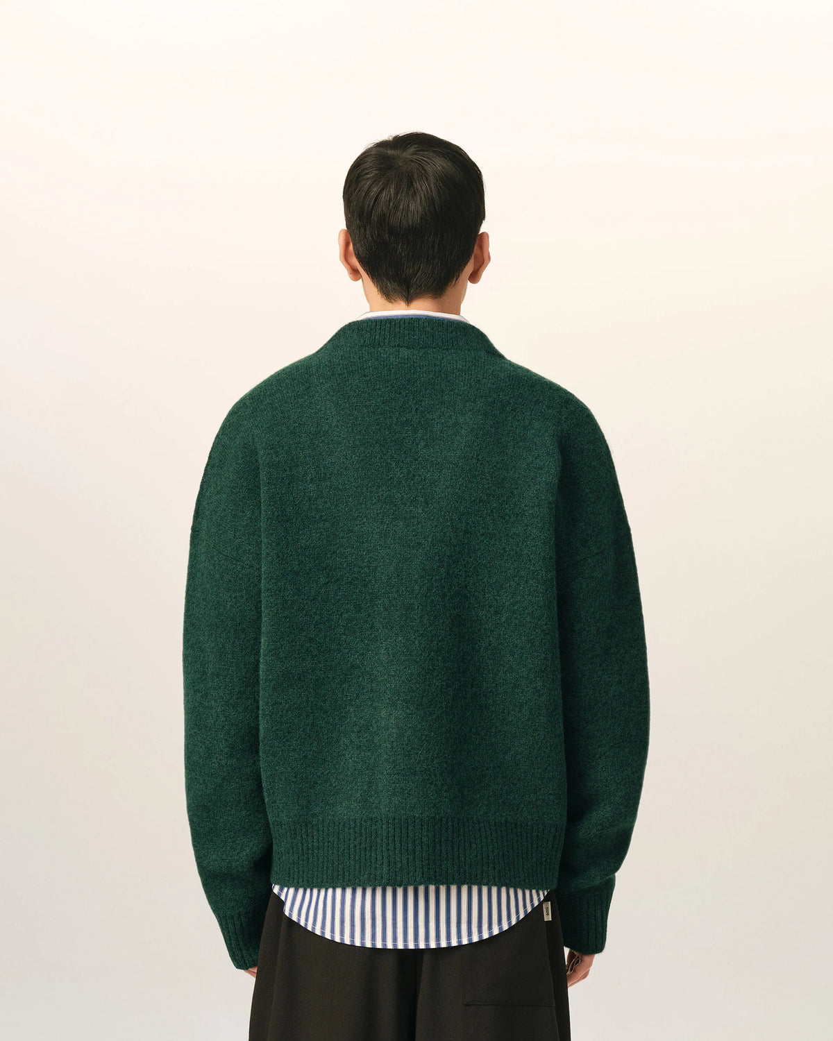 Green cardigan with a heart and 'A' emblem on a beige background