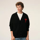Black cardigan with a red heart emblem on a beige background ami paris