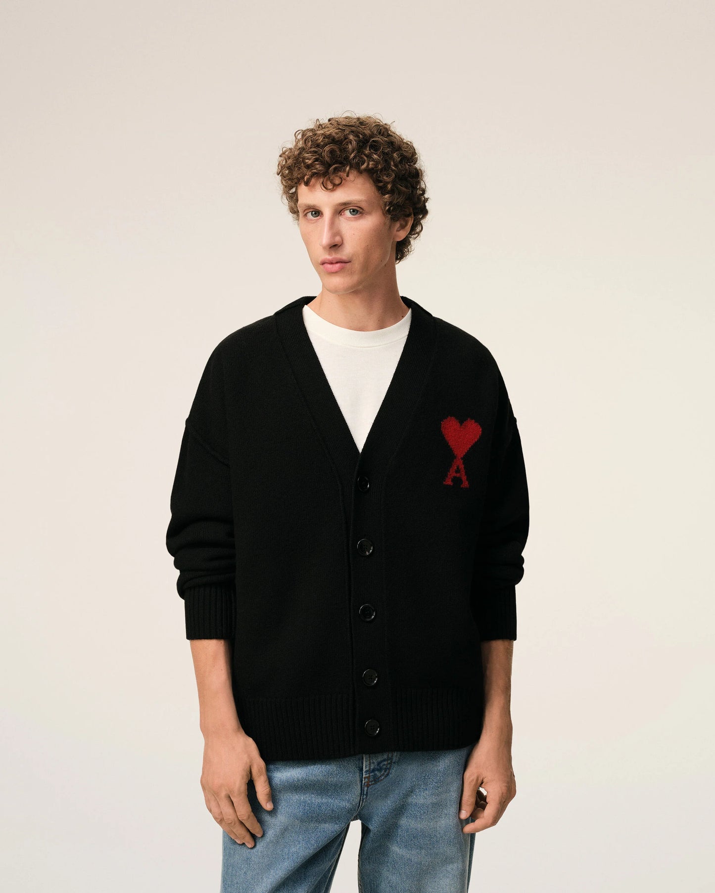 Black cardigan with a red heart emblem on a beige background ami paris