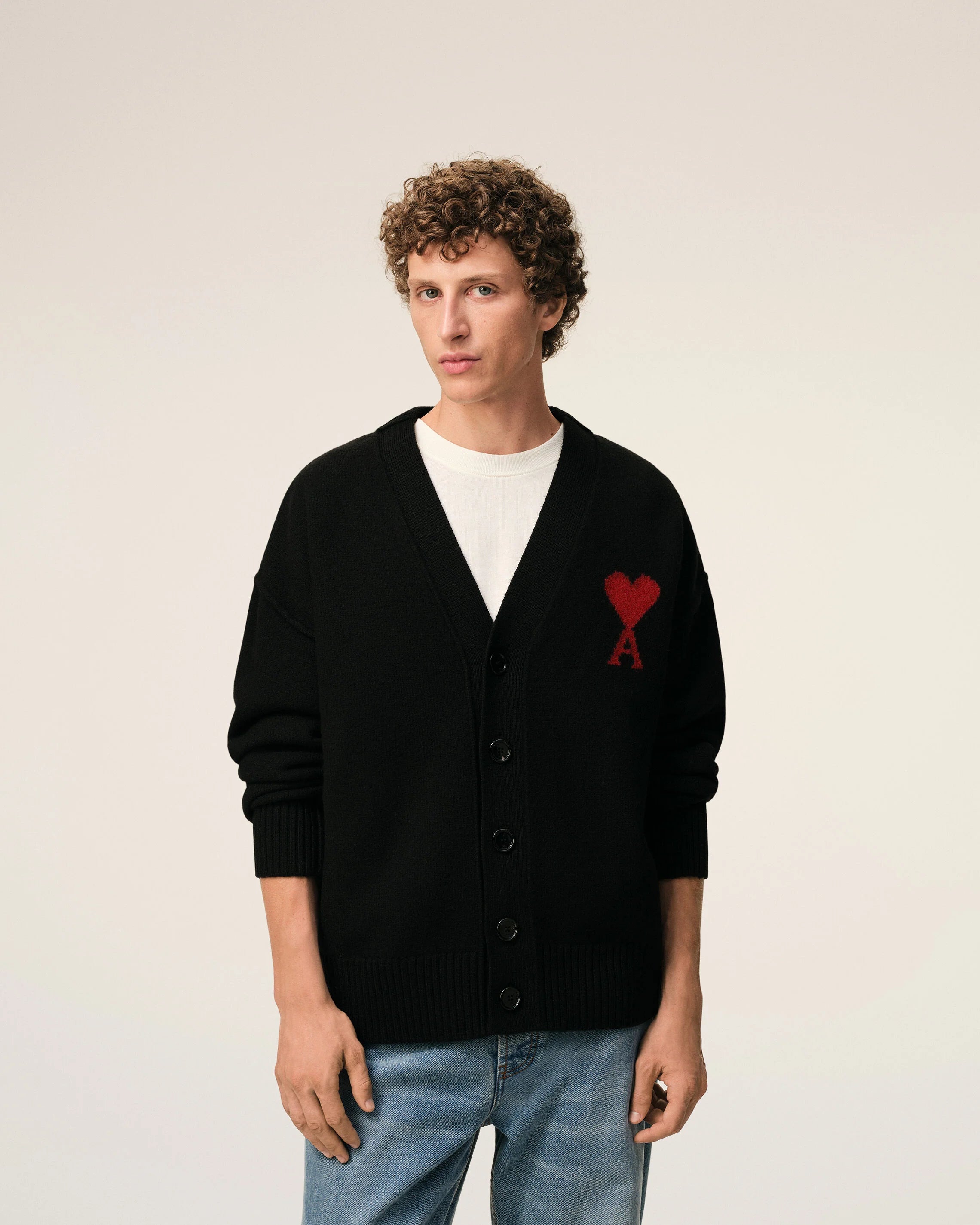 Black cardigan with a red heart emblem on a beige background ami paris