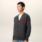 Dark gray cardigan with a red heart emblem on a beige background ami paris