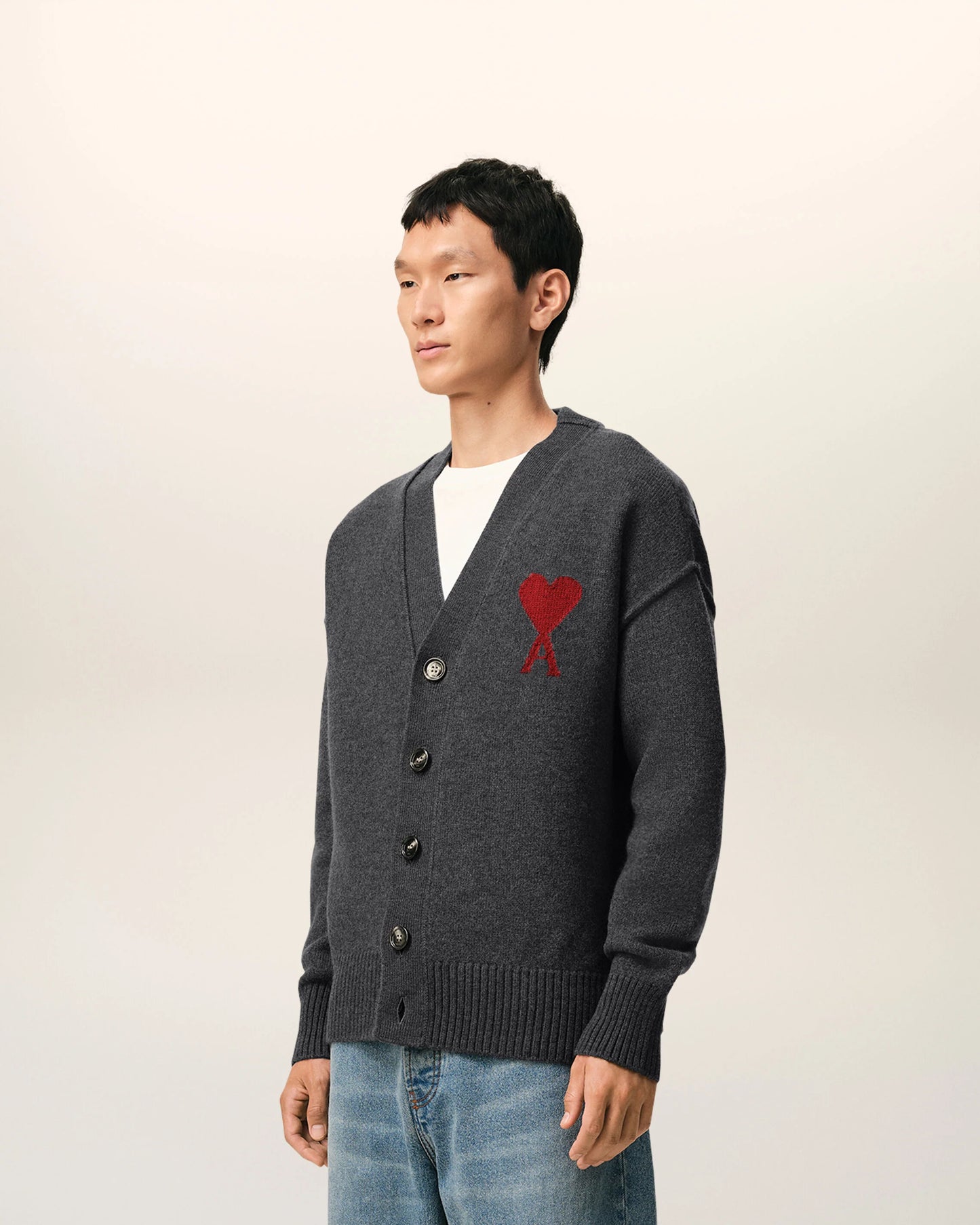 Dark gray cardigan with a red heart emblem on a beige background ami paris