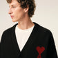 Black cardigan with a red heart emblem on a beige background ami paris