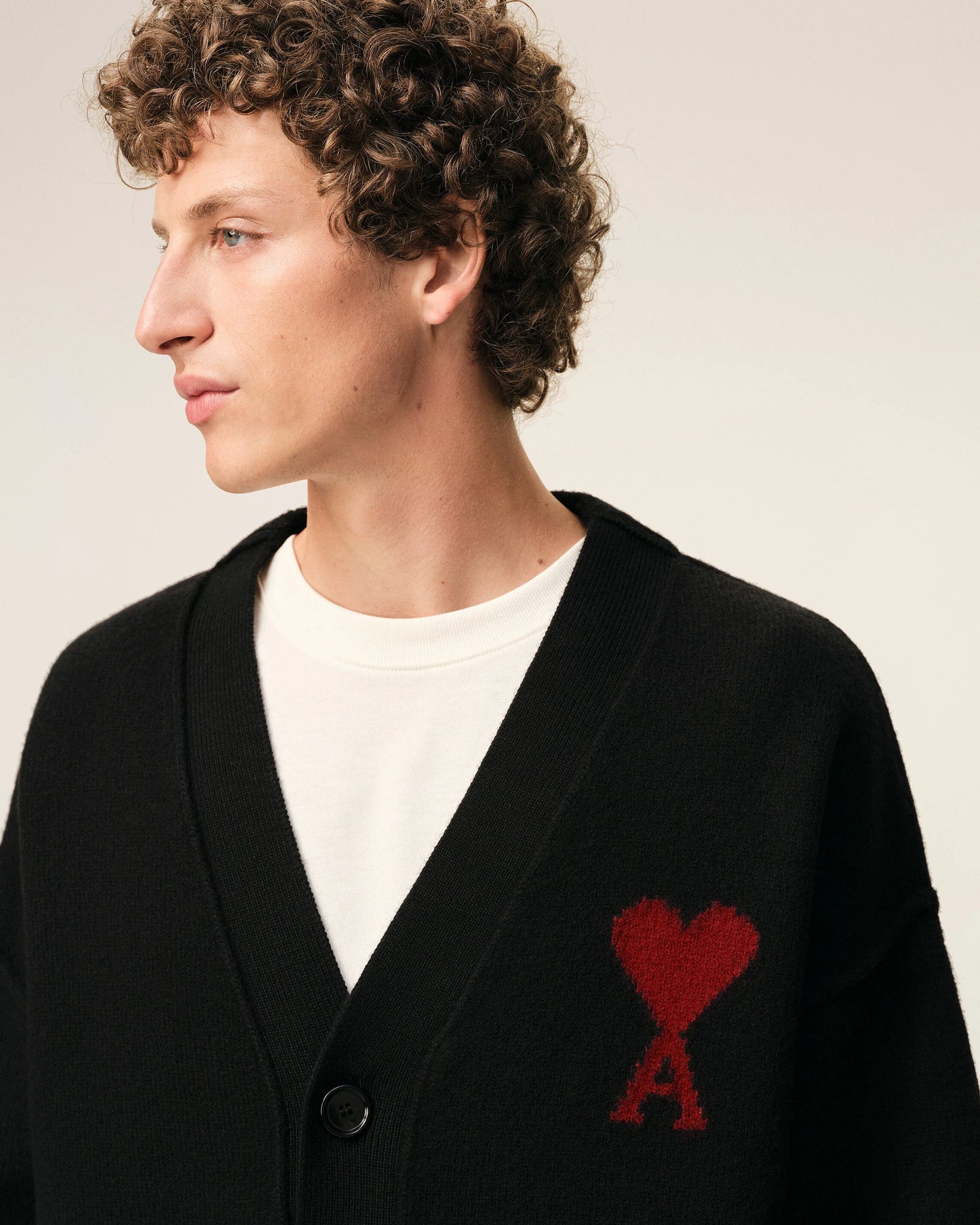 Black cardigan with a red heart emblem on a beige background ami paris