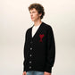 Black cardigan with a red heart emblem on a beige background ami paris