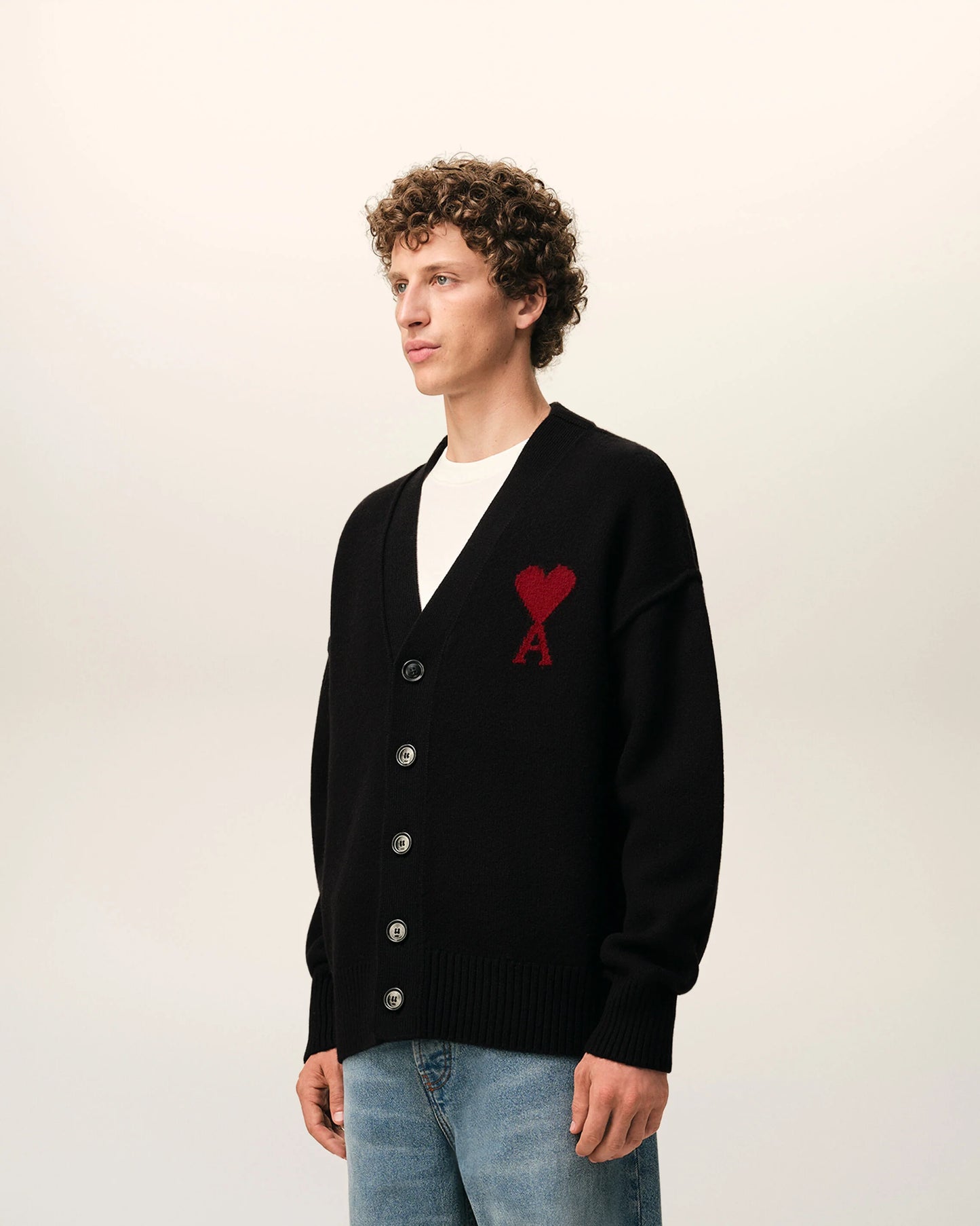 Black cardigan with a red heart emblem on a beige background ami paris