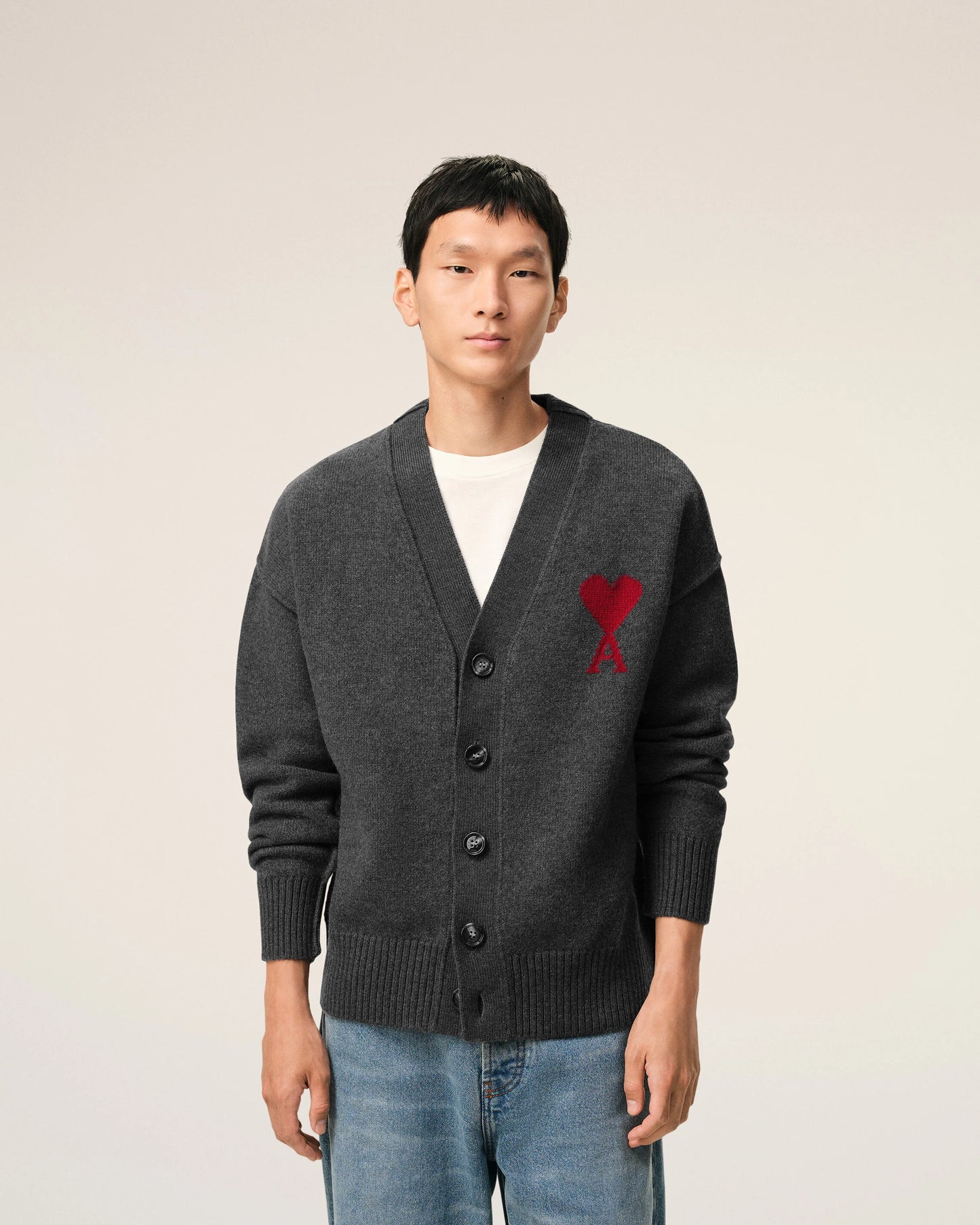 Dark gray cardigan with a red heart emblem on a beige background ami paris