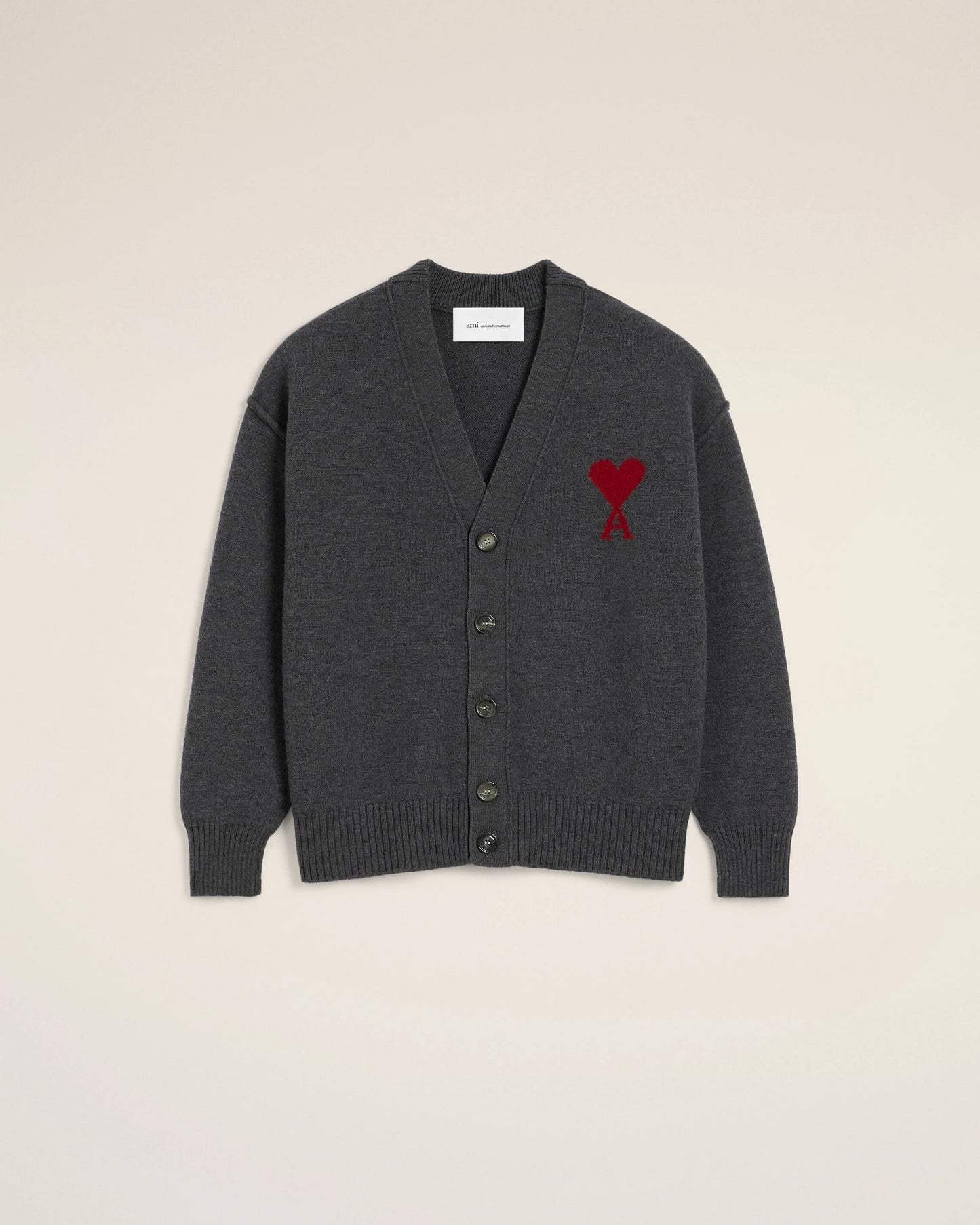 Dark gray cardigan with a red heart emblem on a beige background ami paris