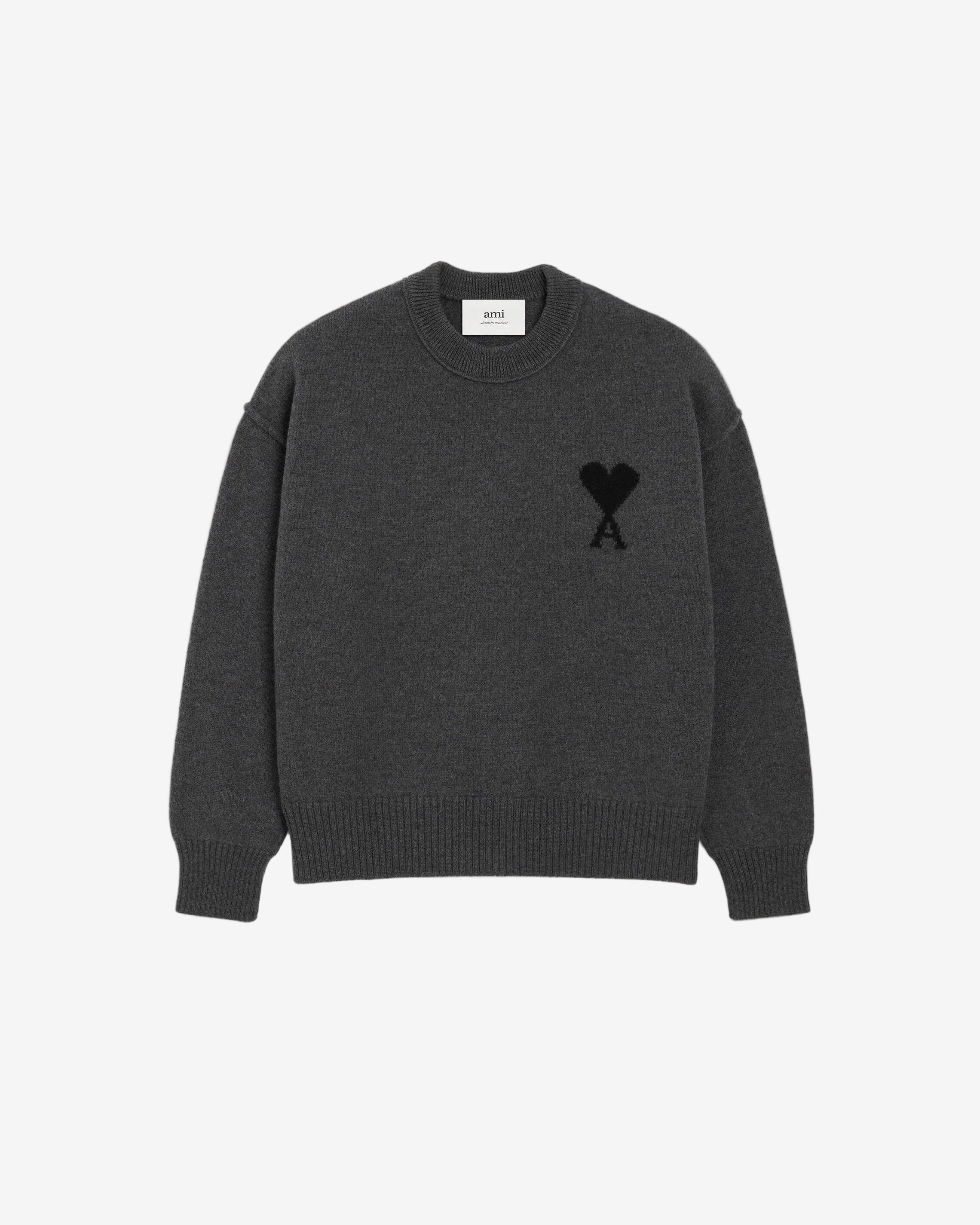 Gray sweater with a black heart and letter 'A' design on a beige background