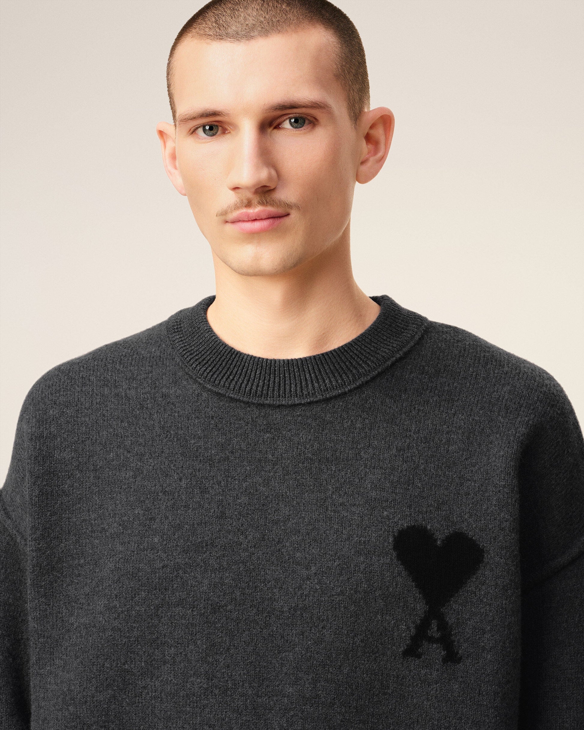Gray sweater with a black heart and letter 'A' design on a beige background