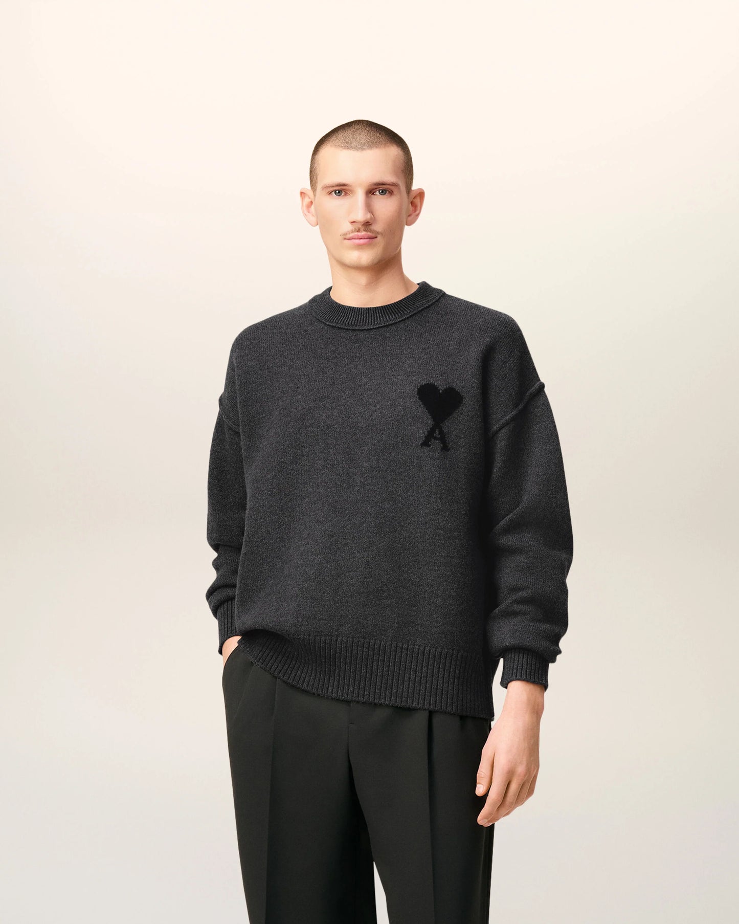 Gray sweater with a black heart and letter 'A' design on a beige background