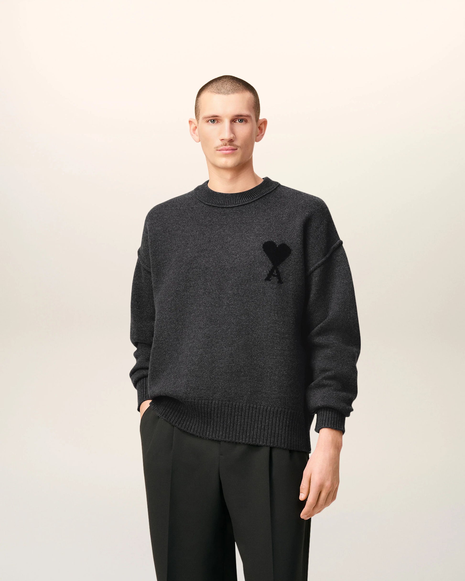 Gray sweater with a black heart and letter 'A' design on a beige background
