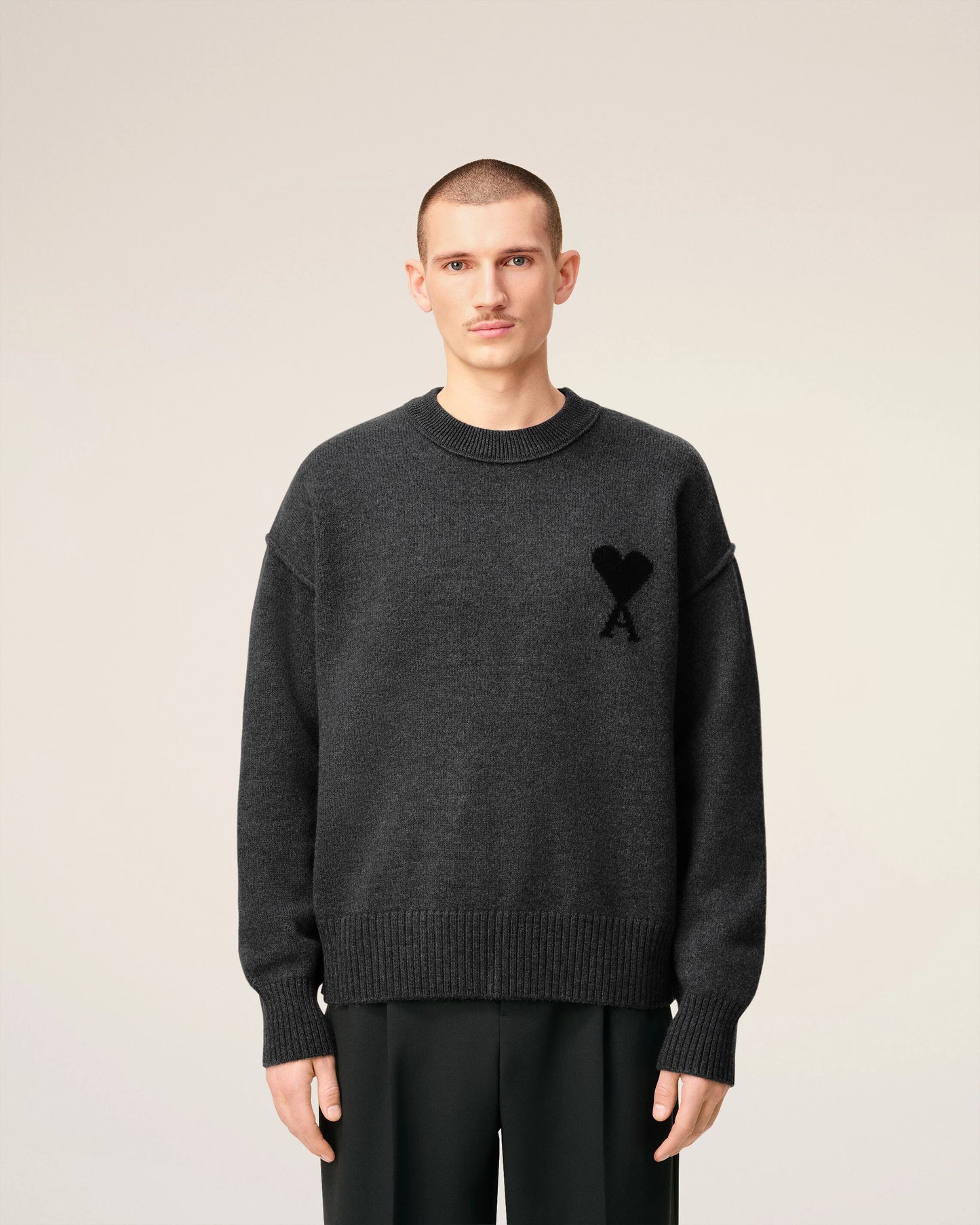 Gray sweater with a black heart and letter 'A' design on a beige background