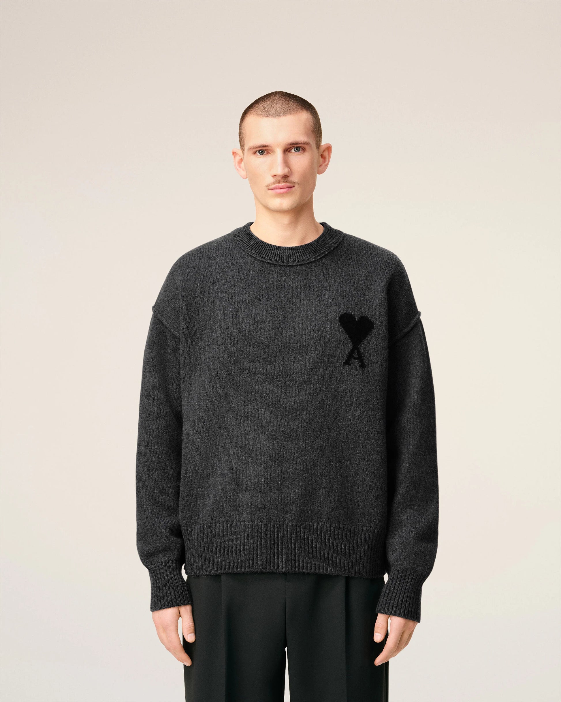 Gray sweater with a black heart and letter 'A' design on a beige background