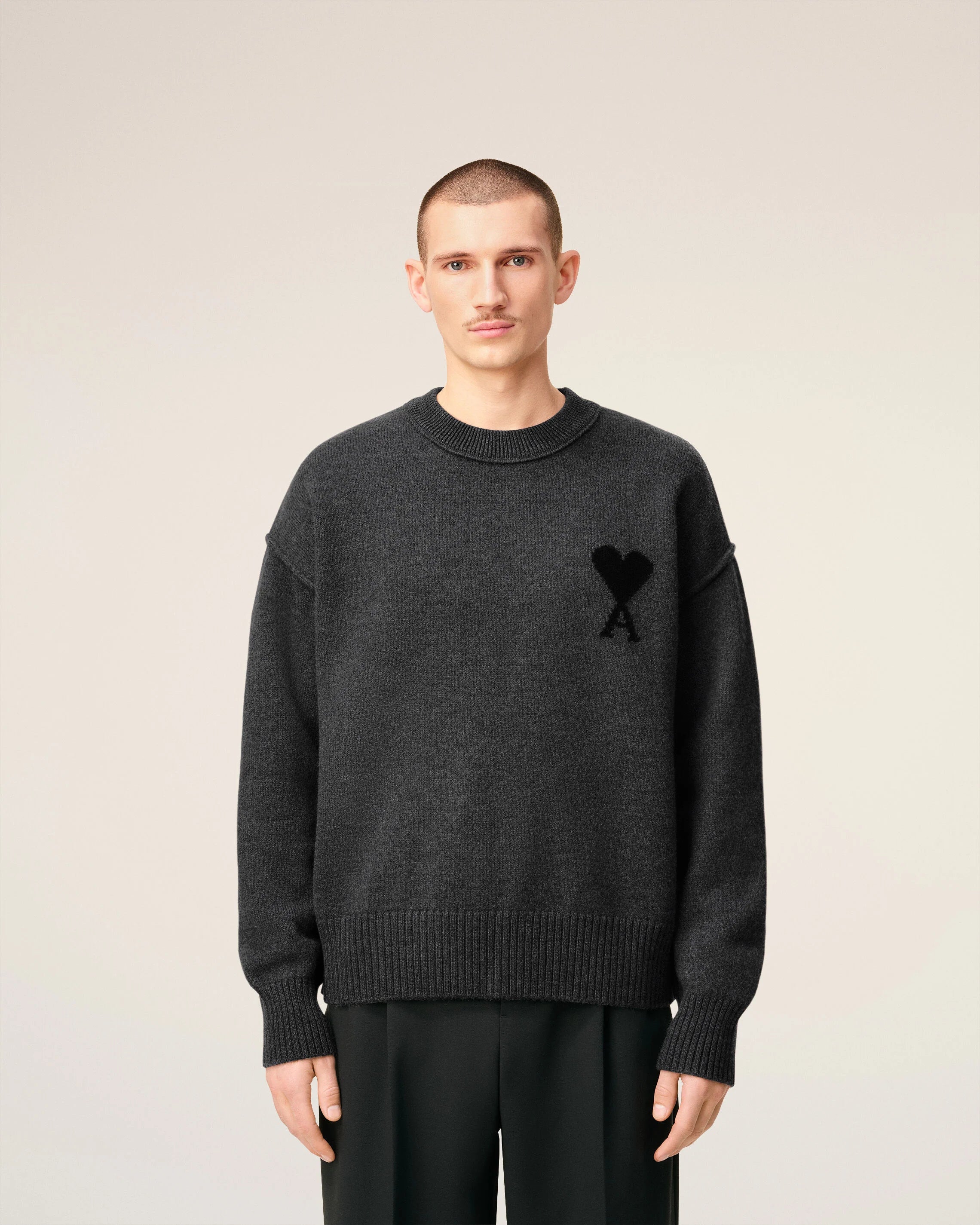 Gray sweater with a black heart and letter 'A' design on a beige background