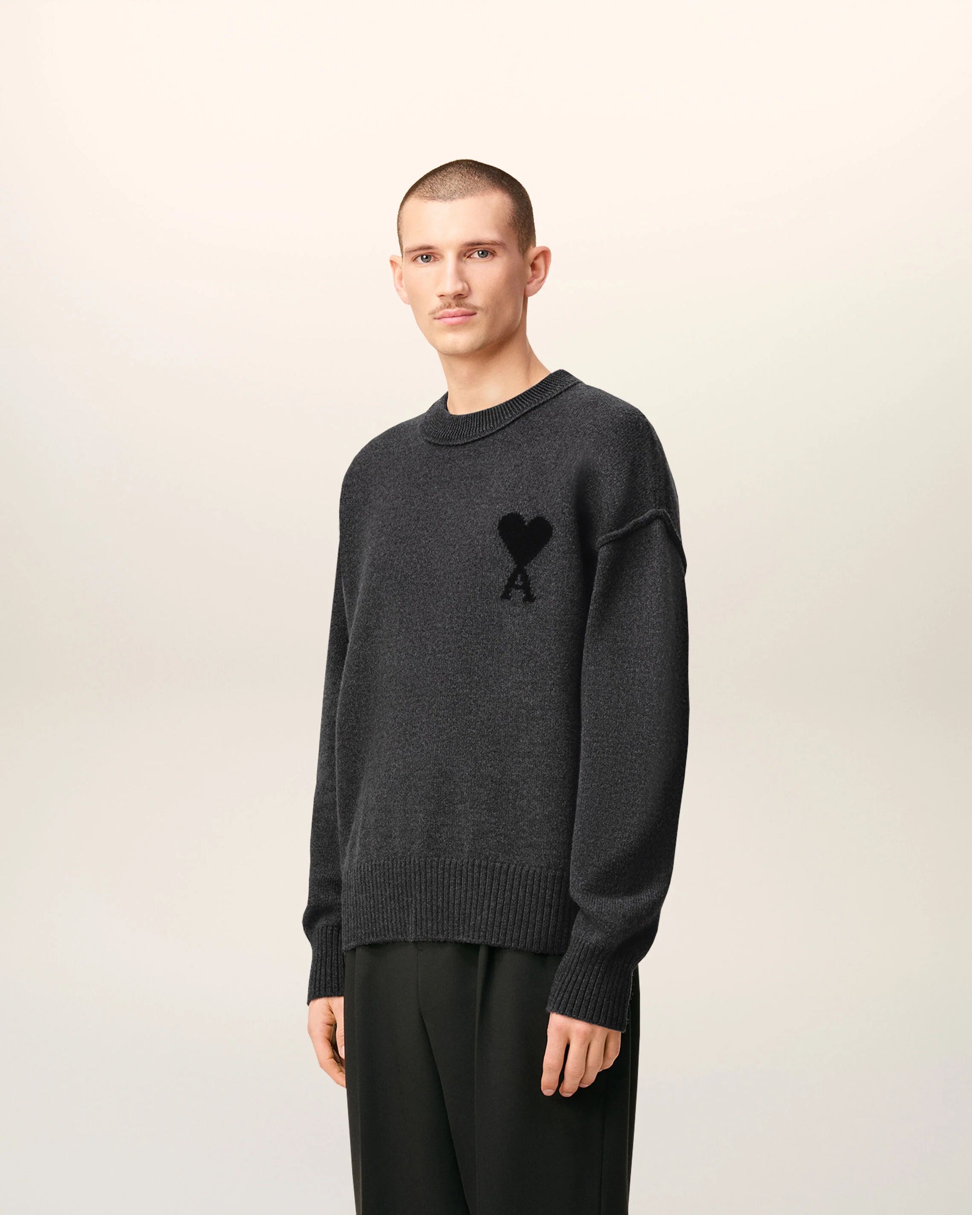 Gray sweater with a black heart and letter 'A' design on a beige background
