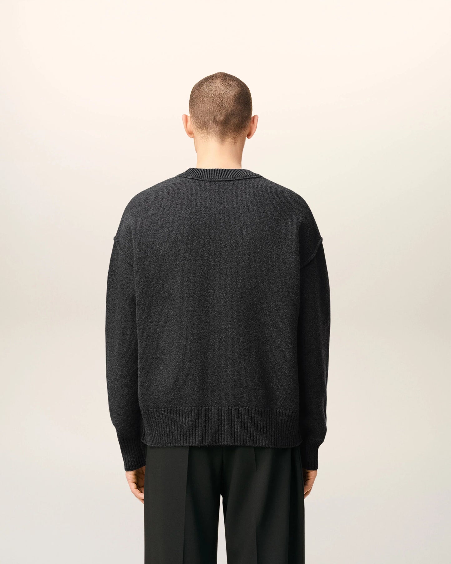Gray sweater with a black heart and letter 'A' design on a beige background