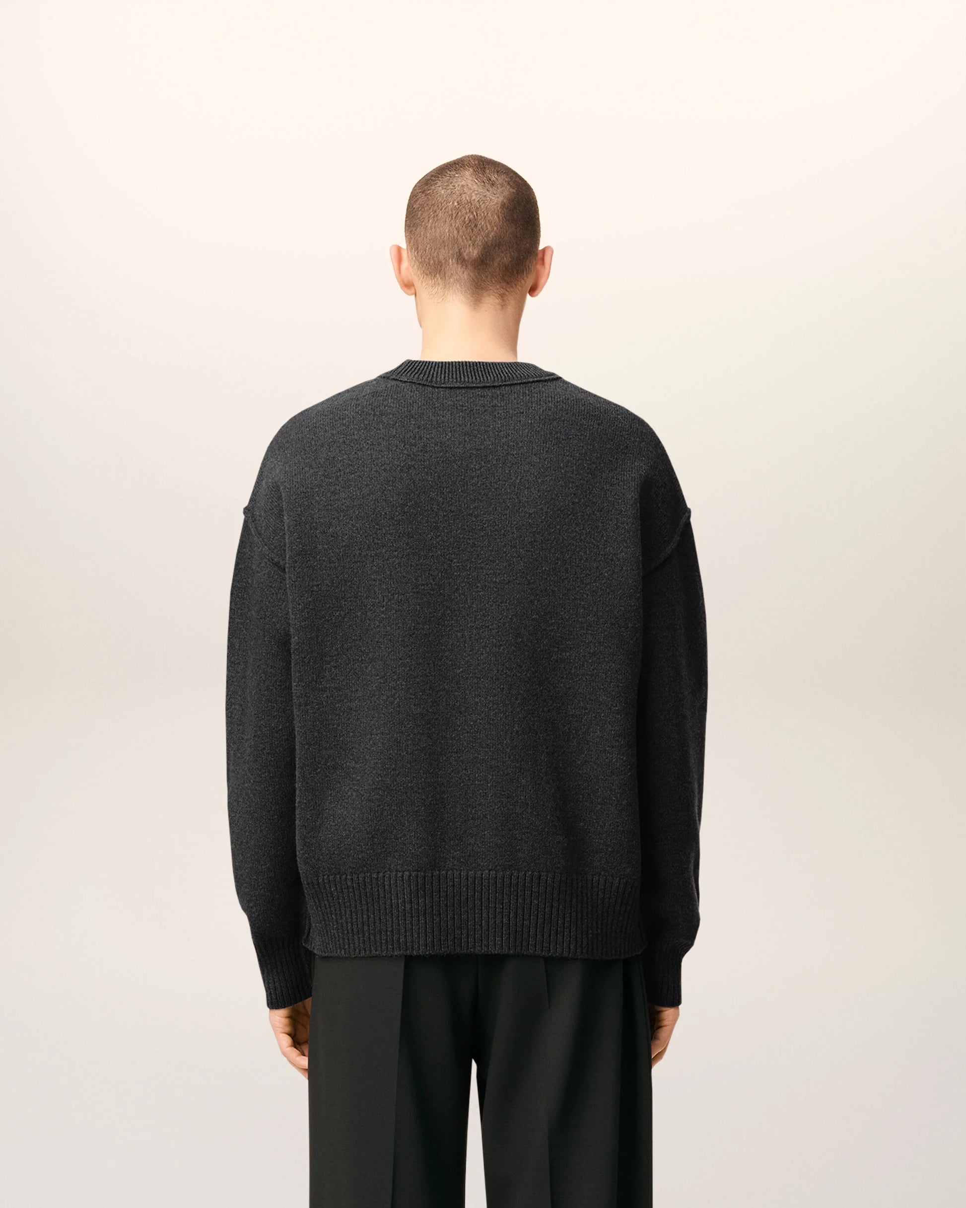 Gray sweater with a black heart and letter 'A' design on a beige background
